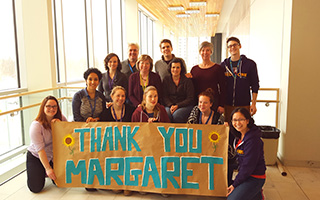 Un groupe de personnes brandit une bannière de remerciement à Margaret!