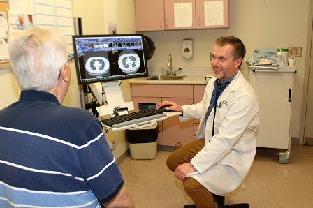 Medical oncologist Dr. Neil Reaume is showing his patient John Richichi, the results of his medical imaging tests right in the exam room