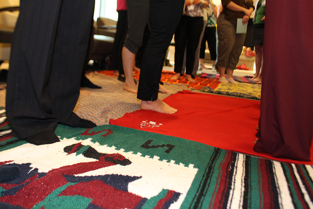 Des membres du personnel se tiennent debout sur des couvertures qui représentent toutes les terres contrôlées par les Autochtones.