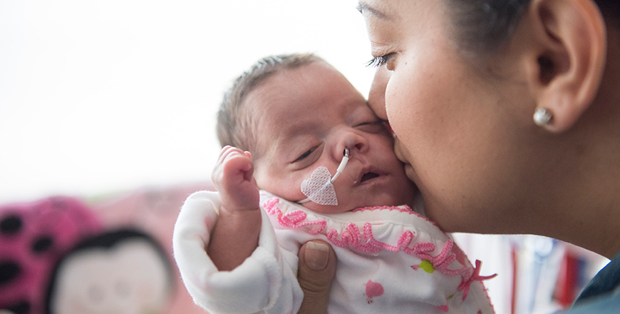 Sarah Sousa gently kisses her tiny baby on the cheek