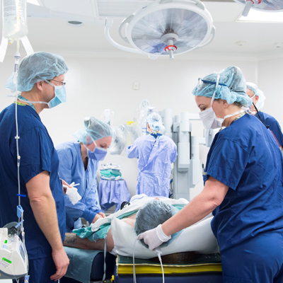 Care providers surround a patient in an operating room