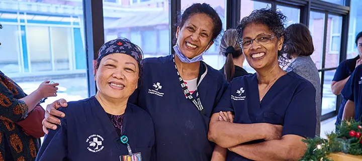 Three hospital employees wearing blue scrubs posing for a photo at Staff Winterfest.