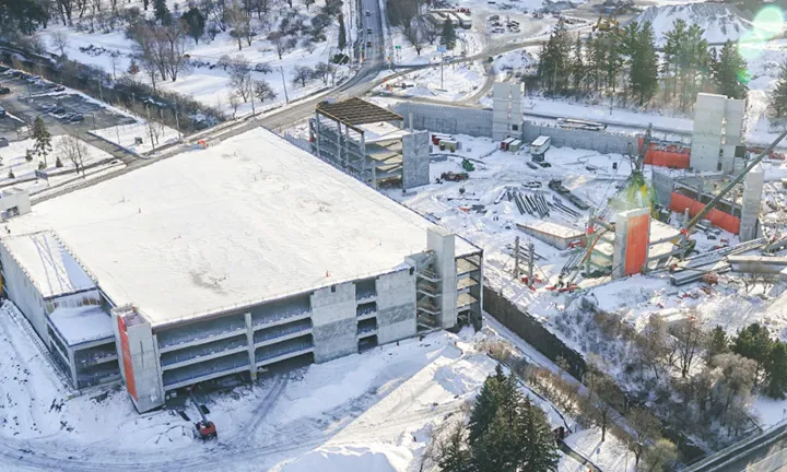 An aerial view in winter of the partially constructed parking garage at The Ottawa Hospital’s new campus. One half of the parking garage is completed and covered by snow, the early stages of construction have begun on the other half.