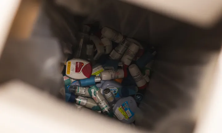 A view into a medical waste container showing a large collection of discarded inhalers.