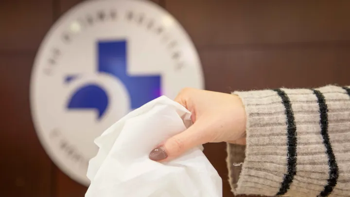 A hand reaches for a box of tissues.