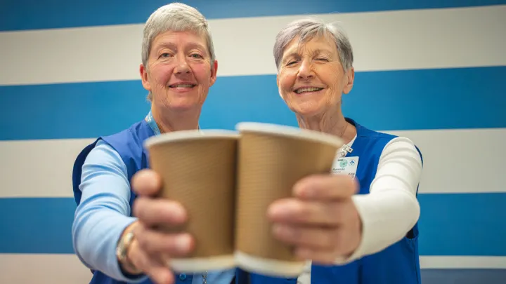 Volunteers Barb McDonald and Moninna Running holding are each holding up a cup of coffee