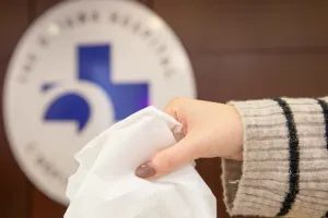 A hand reaches for a box of tissues.
