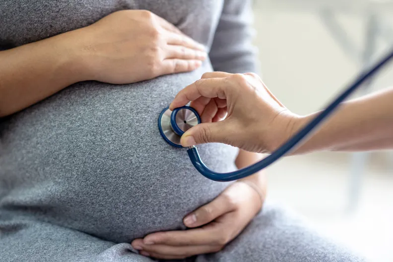 Pregnant person’s belly being examined with a stethoscope.