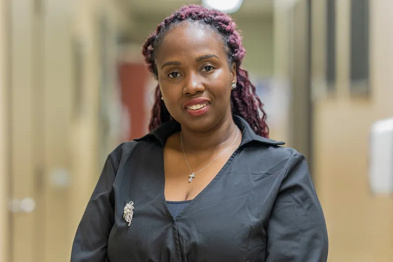 Kaywana Malcolm debout dans le couloir devant le bureau du programme On avance. 