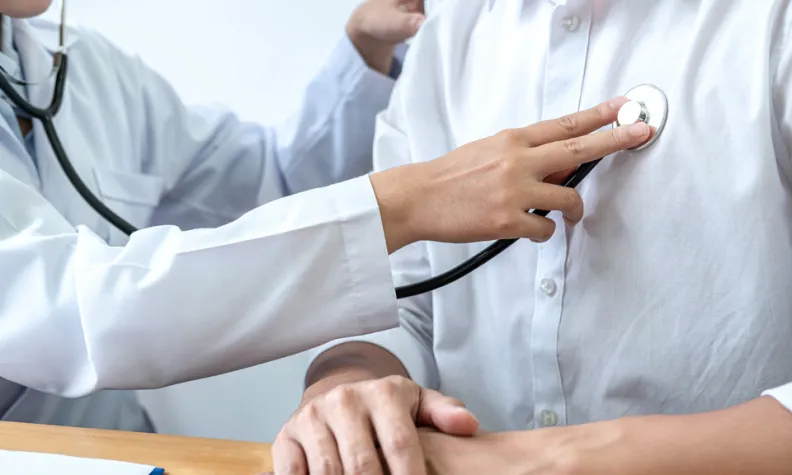 Un médecin utilise un stéthoscope pour écouter la poitrine d’un patient lors d’un examen médical.
