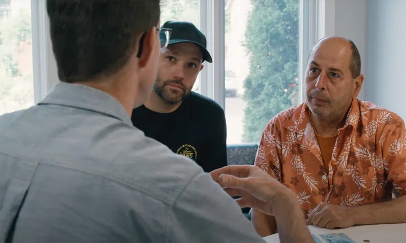 A group of three people sitting at a table, having a conversation.