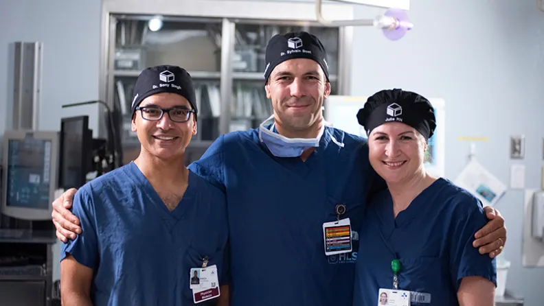 Three TOH staff members in surgical scrubs stand together in a hospital environment.