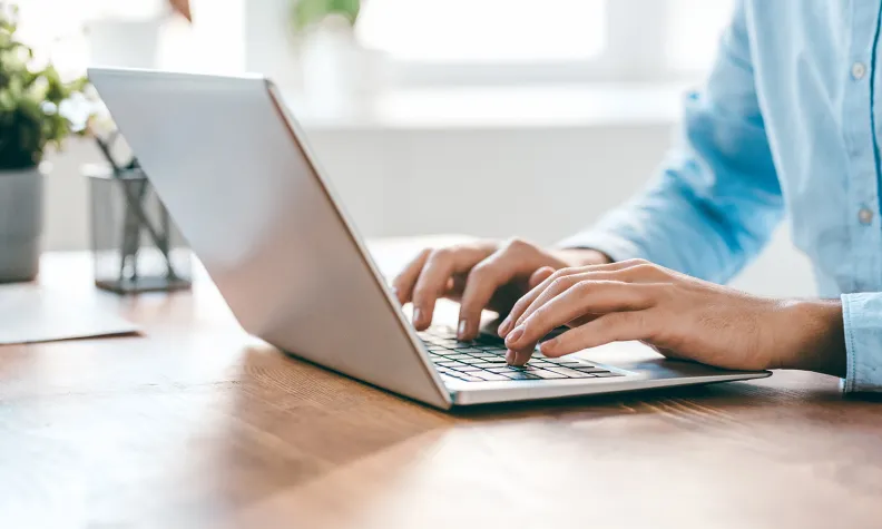 Person typing on a laptop at a desk.