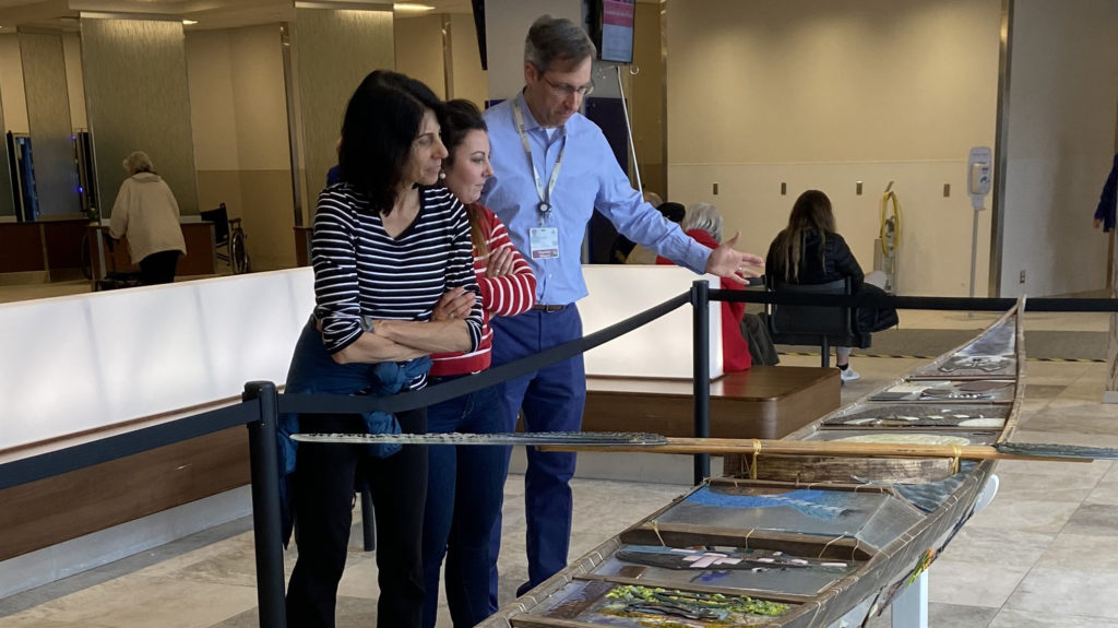 Dr. Anita Gaucher (left), and Trista Bennett, RN, (middle) look at an Inuit art instillation of a 17-foot-long traditional qajaq during their observership of The Ottawa Hospital led by Dr. Tim Asmis (right).