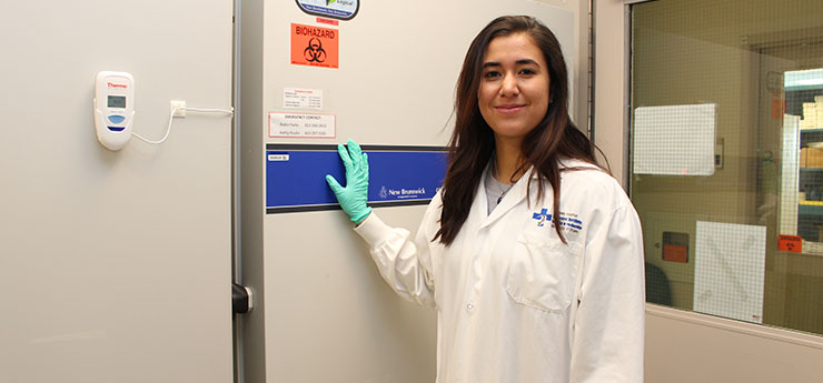 A female researcher is standing next to the freezer