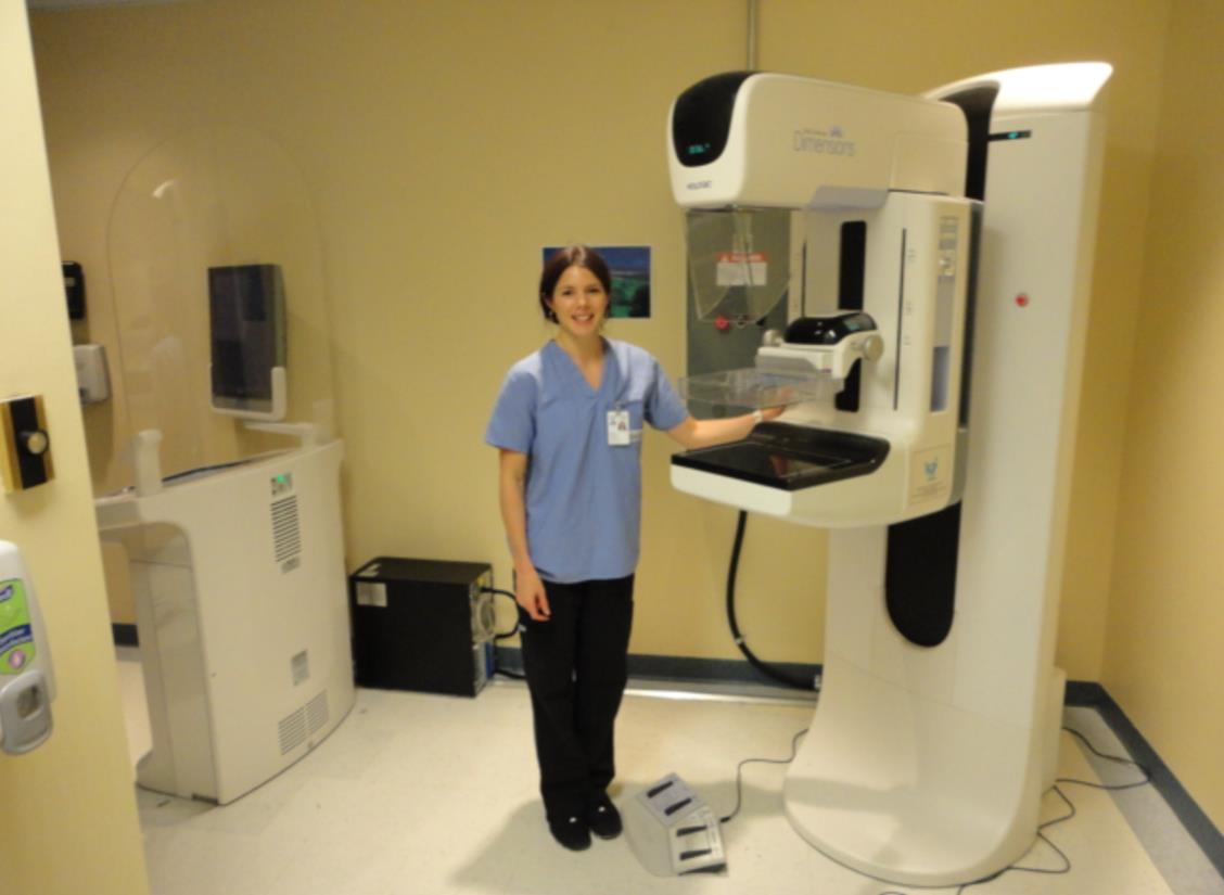 Hospital employee standing next to a mammogram screening machine