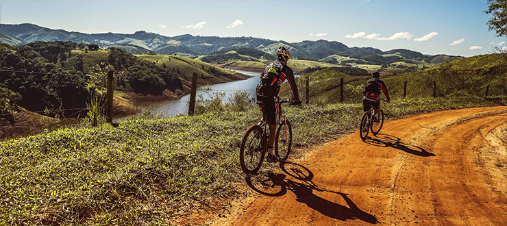 Woman riding a bike along a gravel path at sunset