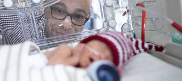 Dr. Bernard Thébaud looks at a premature baby in an isolette.