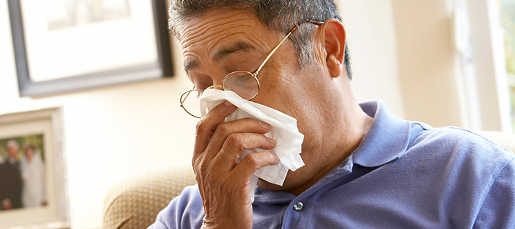 Man sneezes into a tissue