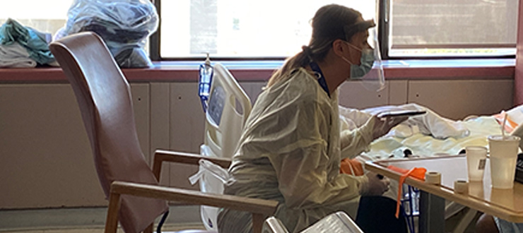 Social Worker Brianna Beck held a tablet for a patient in the hospital’s COVID-19 isolation unit to video chat with their family.