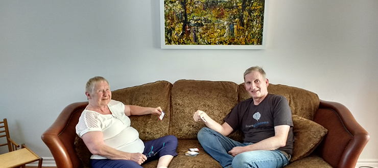 Susan and Ron Wulf sit on a couch playing cards