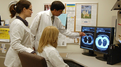 Trois travailleurs à l'hopital qui observent une image prise par tomodensitométrie