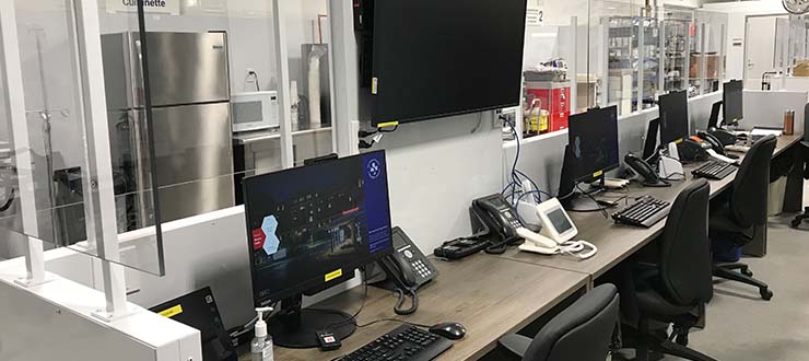 Un poste de travail dans l’Unité, muni d’ordinateurs, d’écrans et de téléphones 