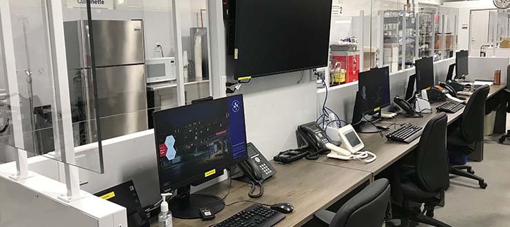 A desk with computers, monitors and telephones in the OMTU