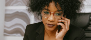 A woman sitting in a black chair talks on her cell phone.