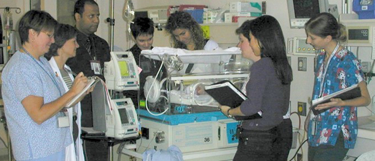 Nurses and doctors oversee a premature baby in an NICU incubator
