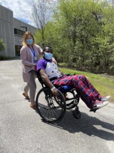 A patient performs a wheelie in a wheelchair supported by physiotherapist Melanie White.