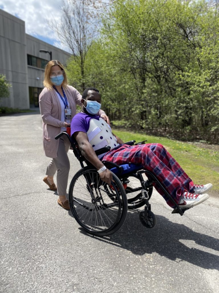 Un patient cabre son fauteuil sur ses roues arrière, avec l’aide de la physiothérapeute Melanie White.