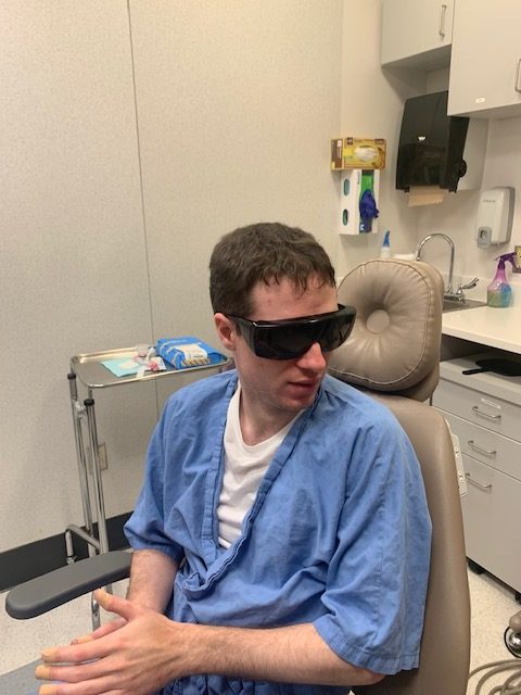 Jean-Marc wearing sunglasses and sitting in a dentist’s chair at The Ottawa Hospital Dental Clinic