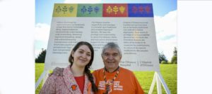 Mairi Brascoupé (left) and Simon Brascoupé standing in front of the land acknowledgement sign that features their original artwork.