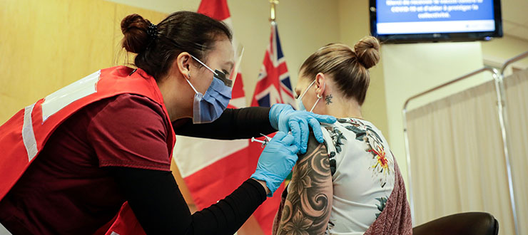 Nurse Venus Lucero administers vaccine to Jo-Anne Miner