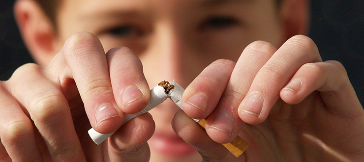 Person breaking a cigarette in half