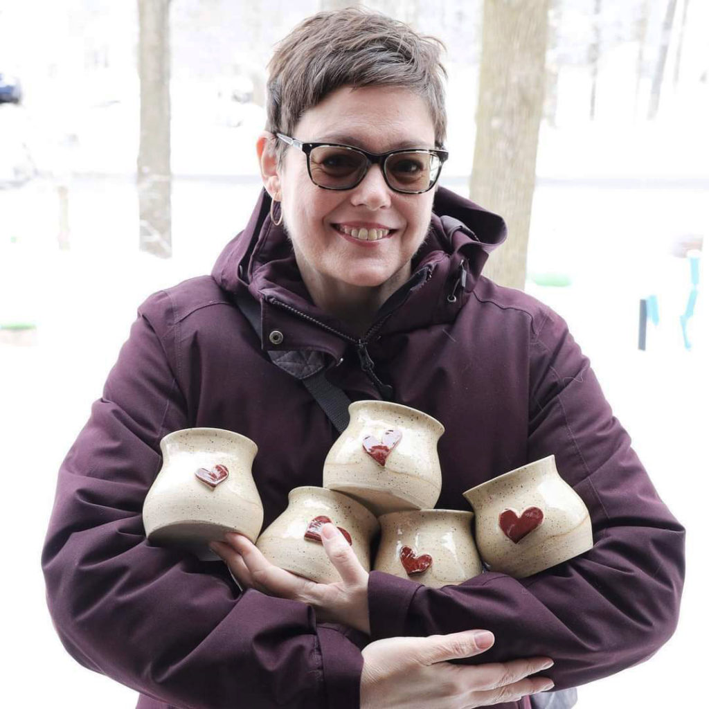 Woman in winter coat carrying five Heart Hug mugs