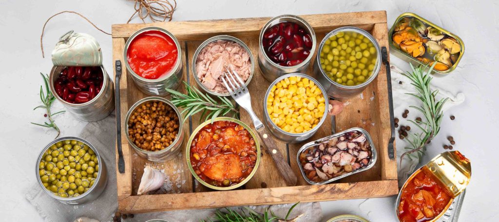 A variety of open cans of food on a wooden tray.