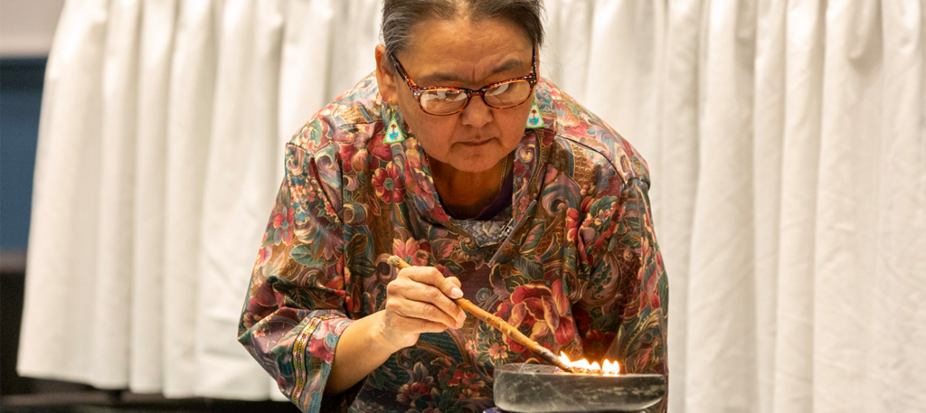 Inuk Knowledge Keeper Meeka Uniuqsarag lights the qulliq, a traditional Inuit oil lamp