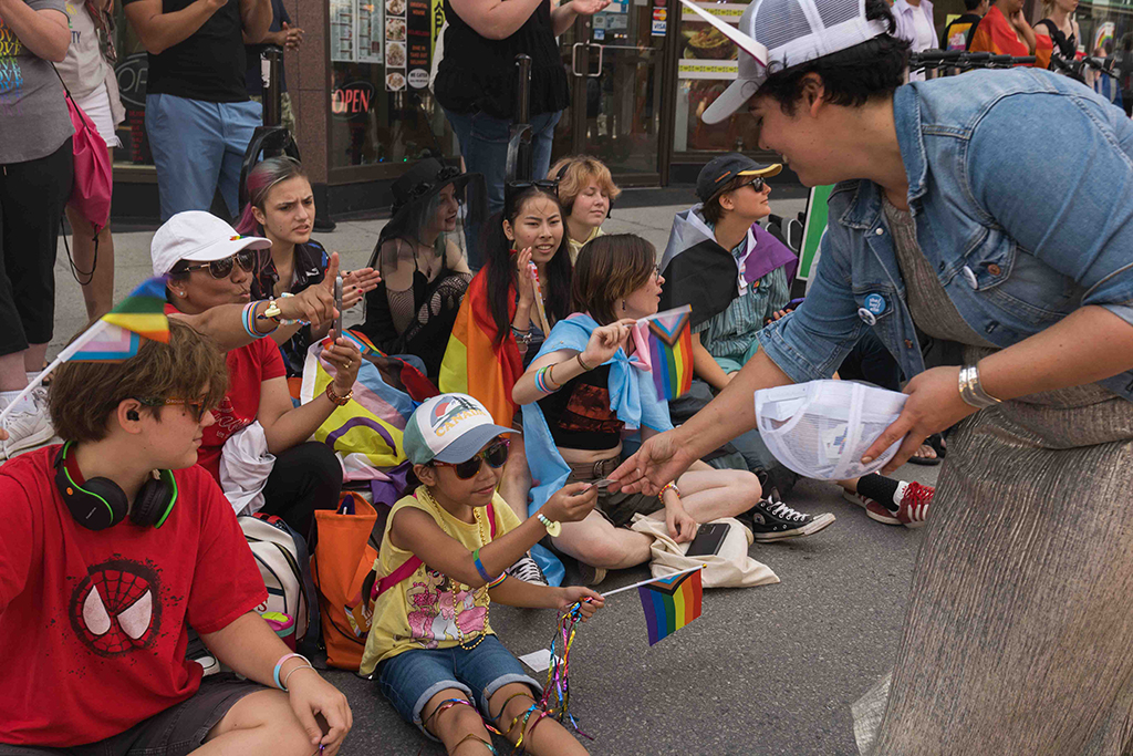 Anya Marion distribue des macarons à des enfants le long du parcours du défilé.