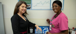 Caiti Wallwork (left), Manager of Clinical Services on the Geriatric Medicine Unit, and Sabrina Duckworth (right), Registered Practical Nurse on the Geriatric Medicine Unit, pose in front of a recycling station in the unit’s kitchenette.