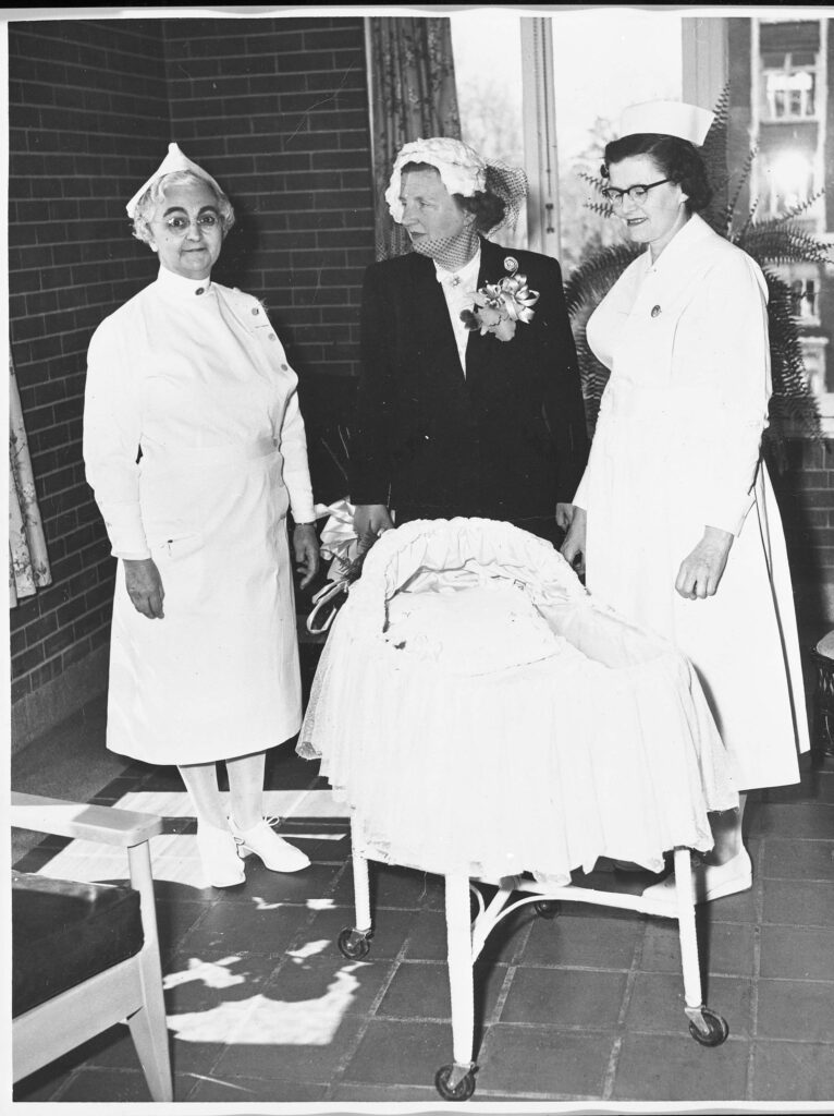 Princess Juliana of the Netherlands with two nurses at the Ottawa Civic Hospital. They are standing around the bassinet that was used following the birth of Princess Margriet in January 1943.
