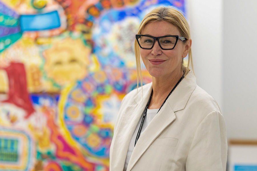 La Dre Mary Marquardt debout devant des créations d’art thérapeutique colorées faites par des clients du programme On avance.
