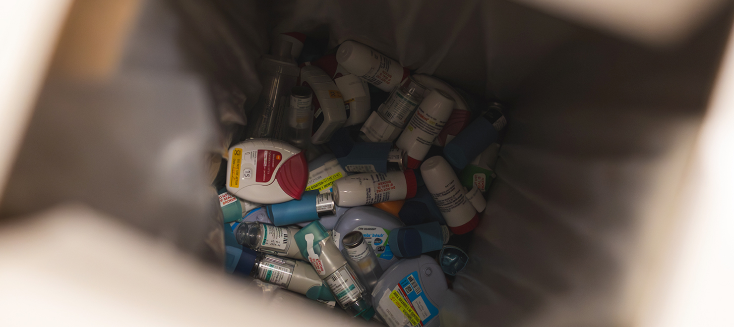 A view into a medical waste container showing a large collection of discarded inhalers.